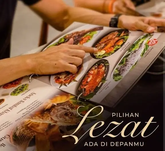 Tangan pelanggan sedang menunjuk pilihan menu ikan bakar lezat pada buku menu fisik untuk menggambarkan hasil dari strategi pemasaran digital.