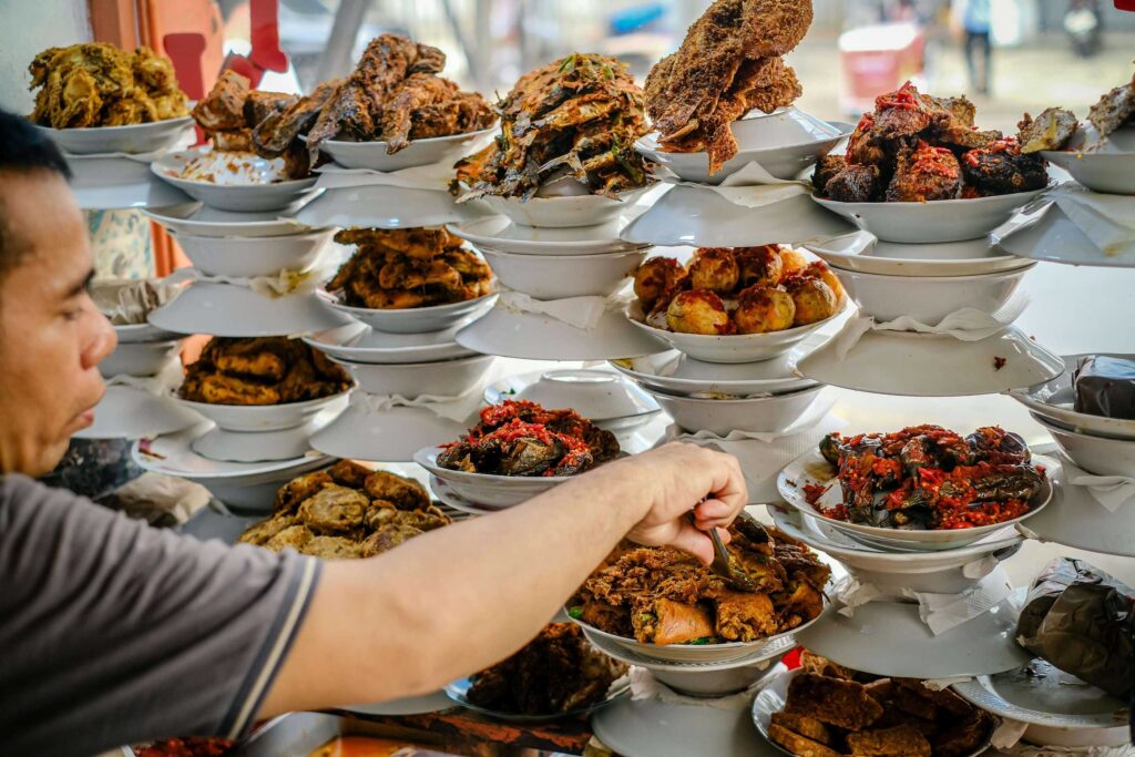 Pelanggan memilih aneka lauk dan masakan tradisional di rumah makan UMKM Indonesia sebagai ilustrasi pentingnya promosi online UMKM kuliner, branding digital, dan strategi SEO bisnis makanan agar lebih dikenal pelanggan