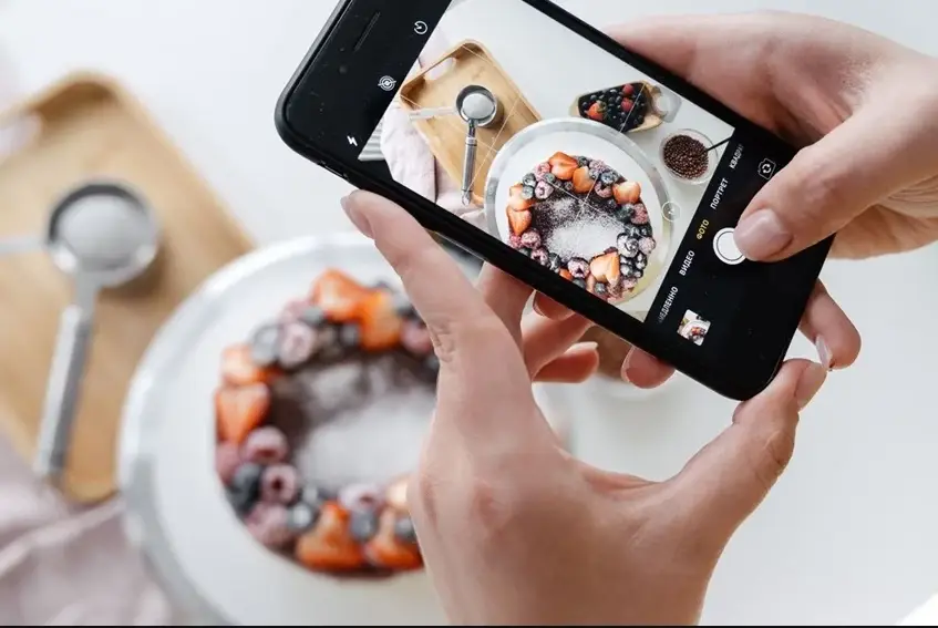Meja dengan properti dekorasi dan kue tart buah yang sudah ditata sebelum sesi foto makanan
